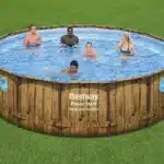 בריכה עגולה מעל הקרקע דוגמת ראטאן עם חלונות צד, עם אנשים שוחים בפנים | yrz